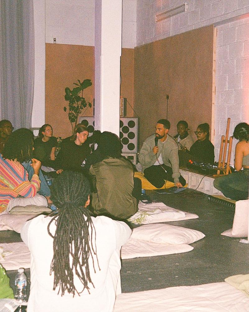 Guests sitting in a circle on cushions during a talk
