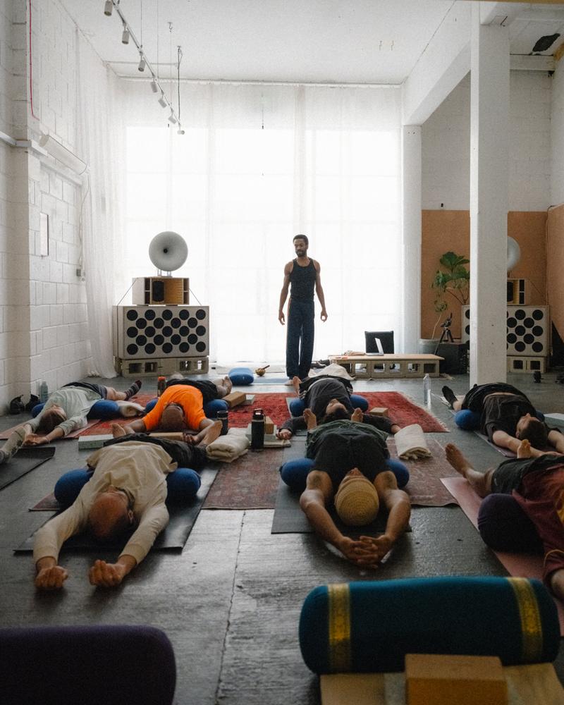 A yoga class lying on mats in the daylit room